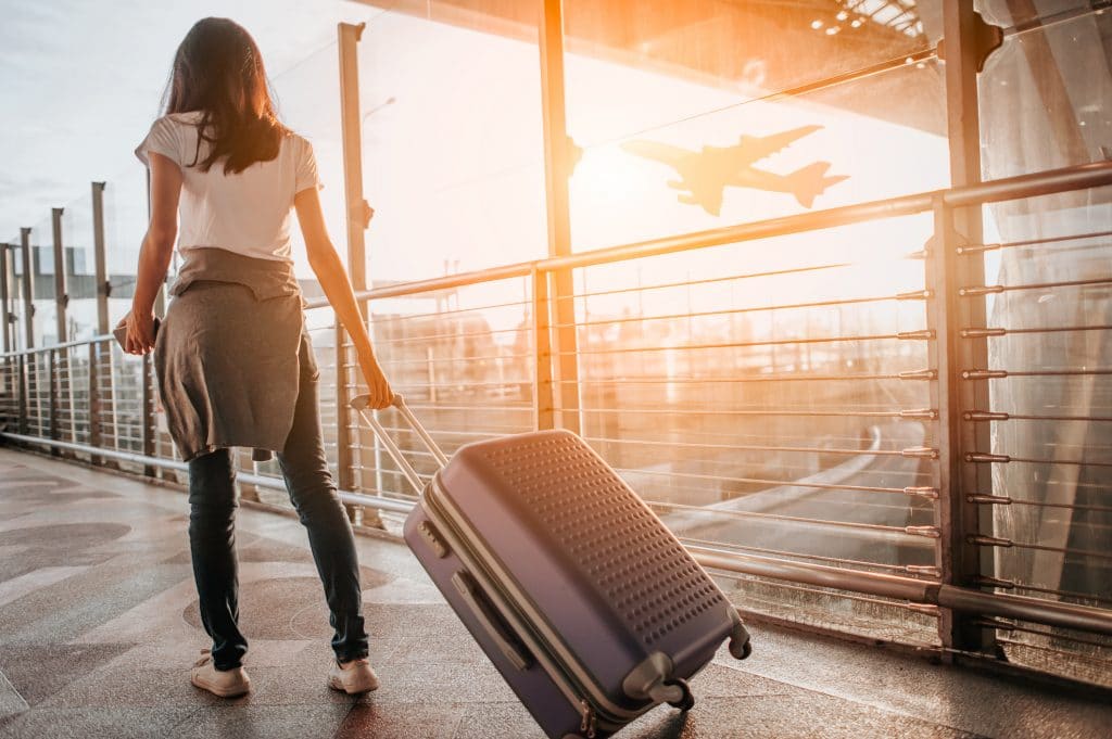 Jeune fille avec sa valise à l'aéroport, qui part en séjour linguistique