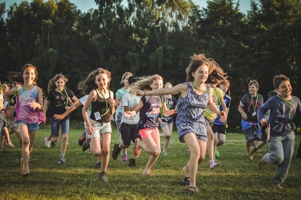 Enfants heureux qui courent dans l'herbe durant leur séjour en summer camp