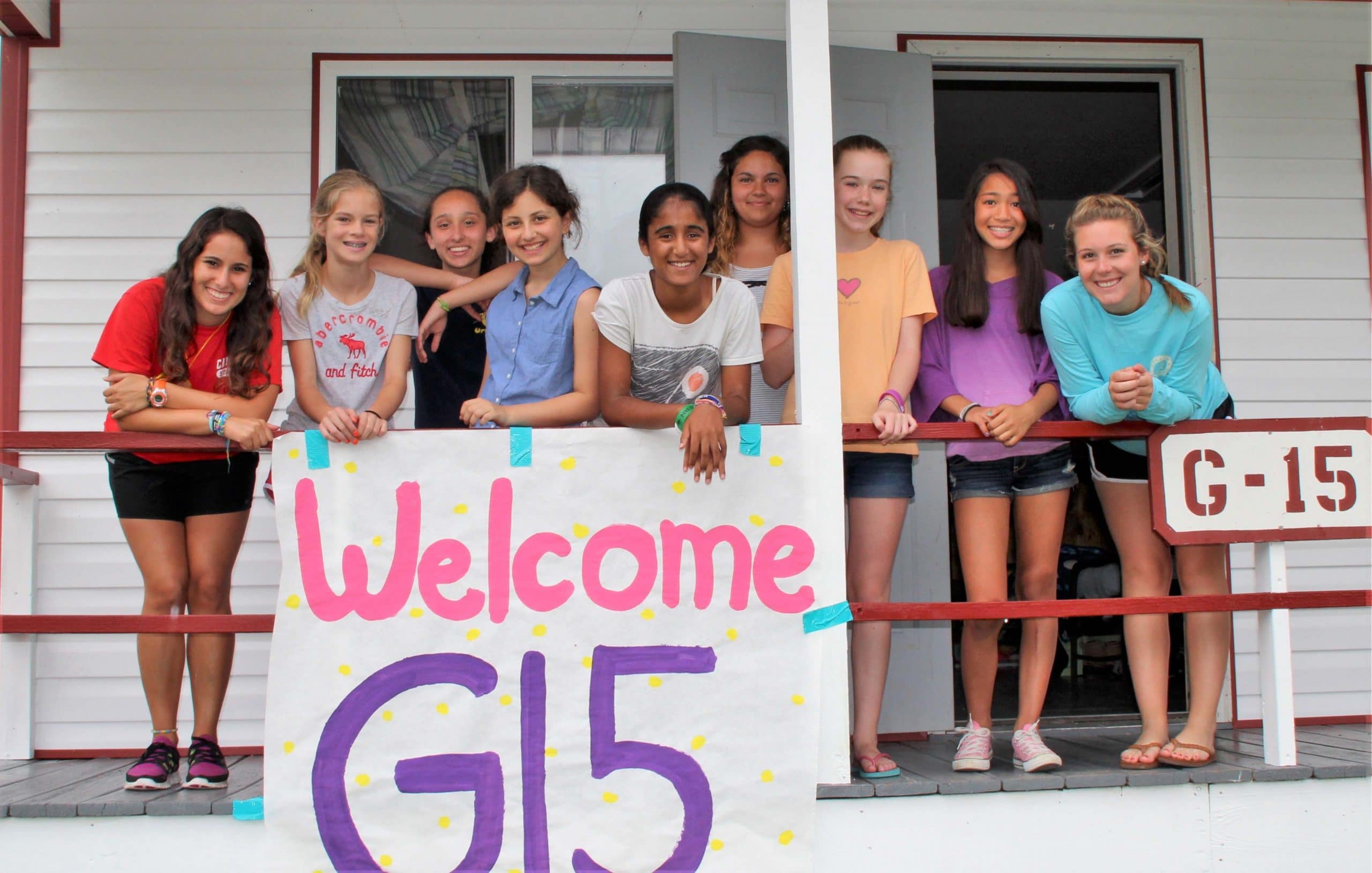Jeunes filles et leurs monitrices posant devant leur cabines durant leur summer camp aux USA