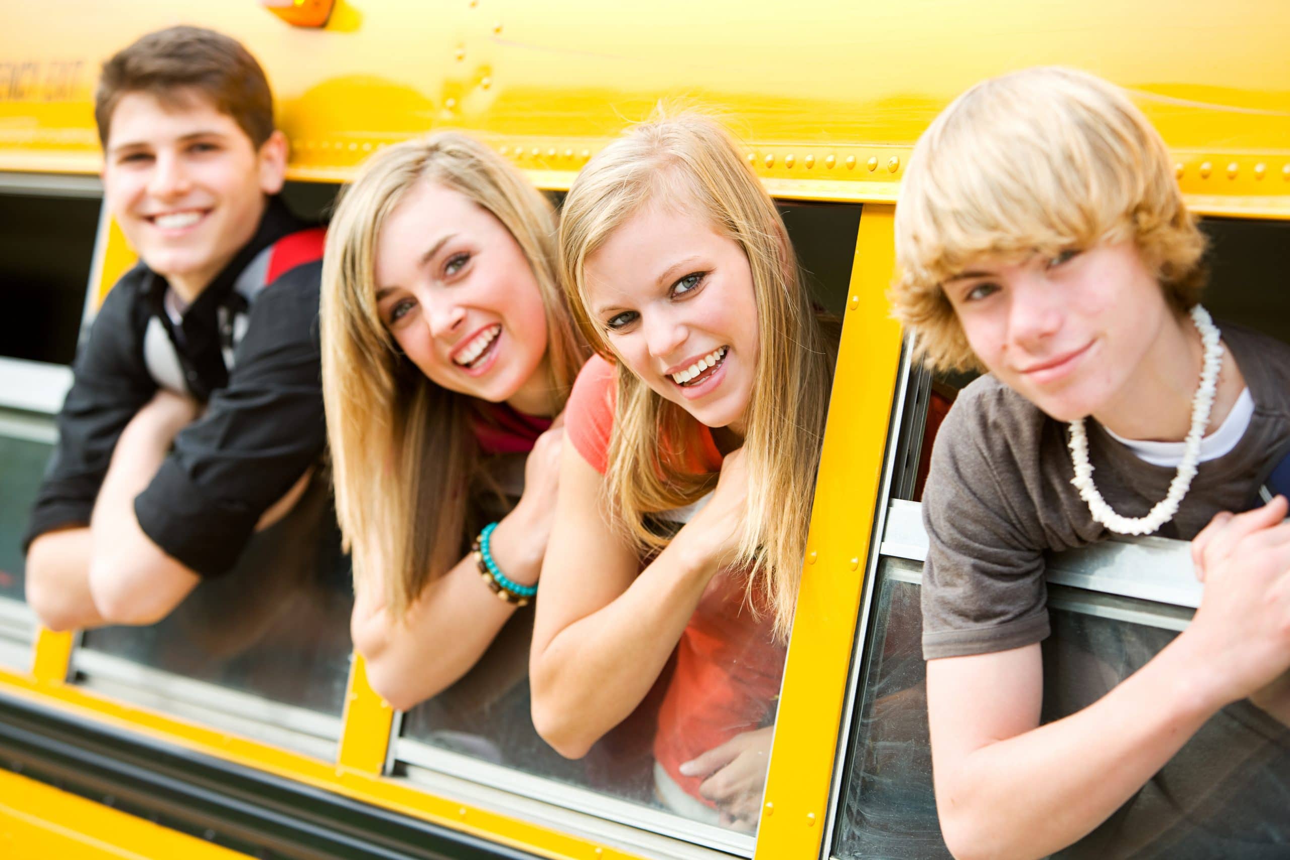 Quatre jeunes se faisant prendre en photo dans un bus scolaire typique américain