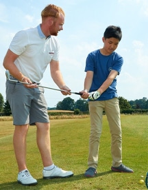 Jeune garçon apprenant à jouer au golf en séjour linguistique